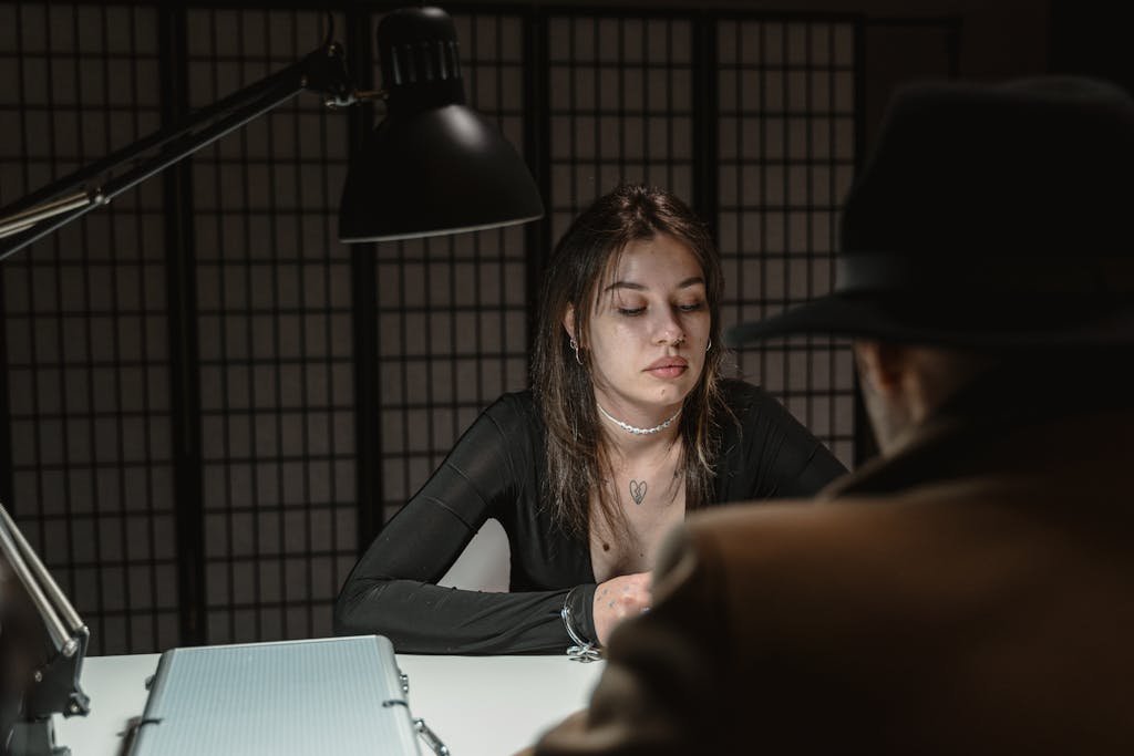 Woman in Black Long Sleeve Shirt Sitting Beside Table